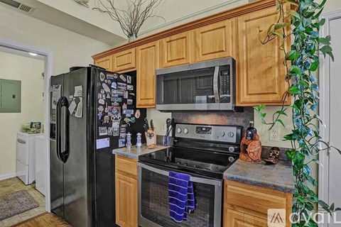 A kitchen with wooden cabinets and a black refrigerator.