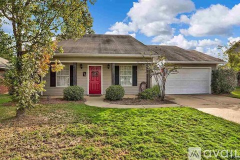 A house with a red door is surrounded by a green lawn.