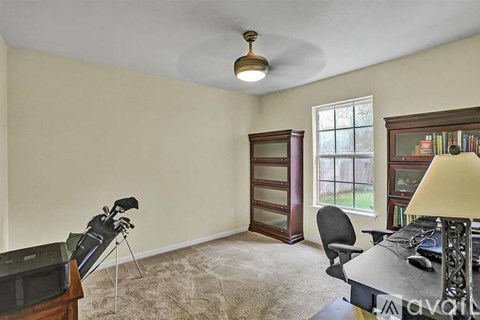 A room with a desk, chair, and a television.