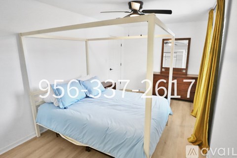 A bedroom with a four-poster bed and a ceiling fan.