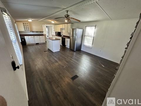 A spacious kitchen with white cabinets and a wooden floor.