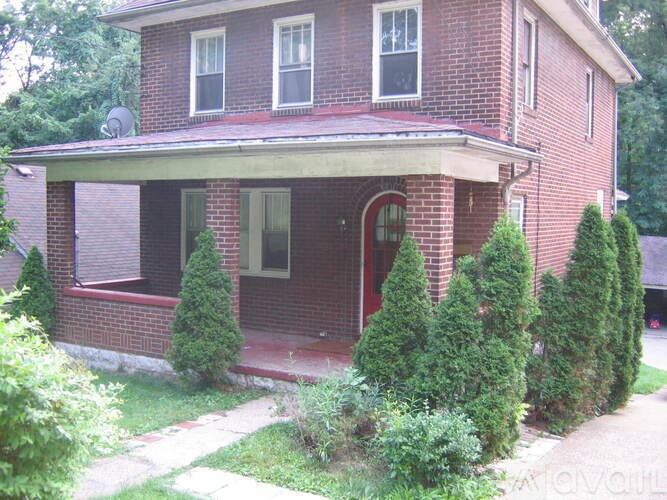 A red brick house with a red door and a small porch.
