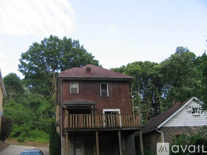 A house with a balcony is surrounded by trees.