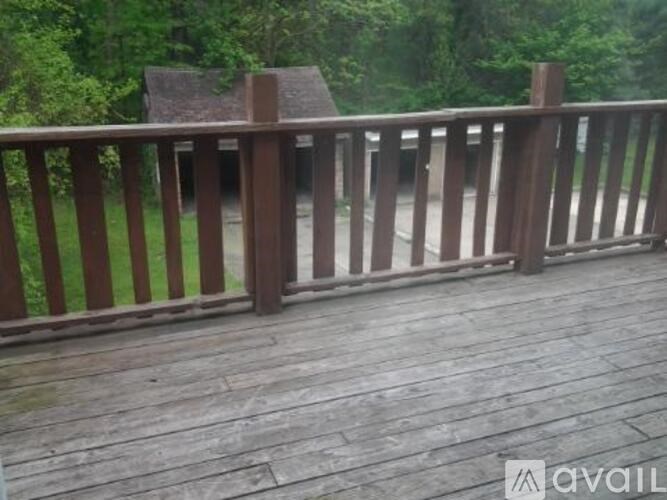 A wooden deck with a railing and a building in the background.