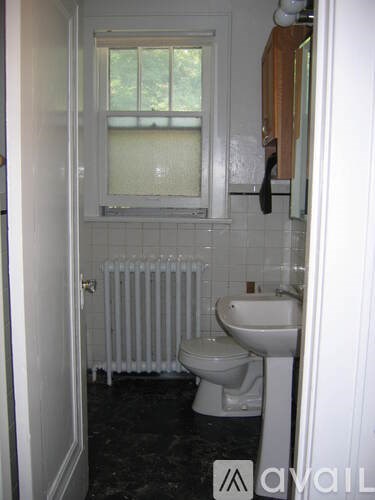 A bathroom with a toilet, sink and a window.
