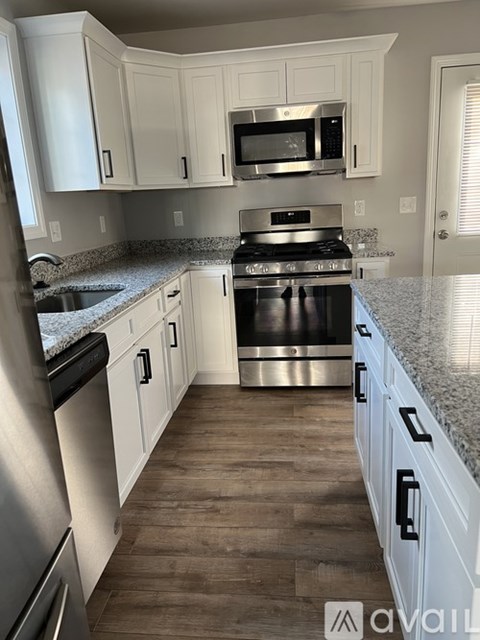 A kitchen with white cabinets and a granite countertop.