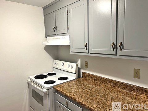 A kitchen with a white stove and cabinets.