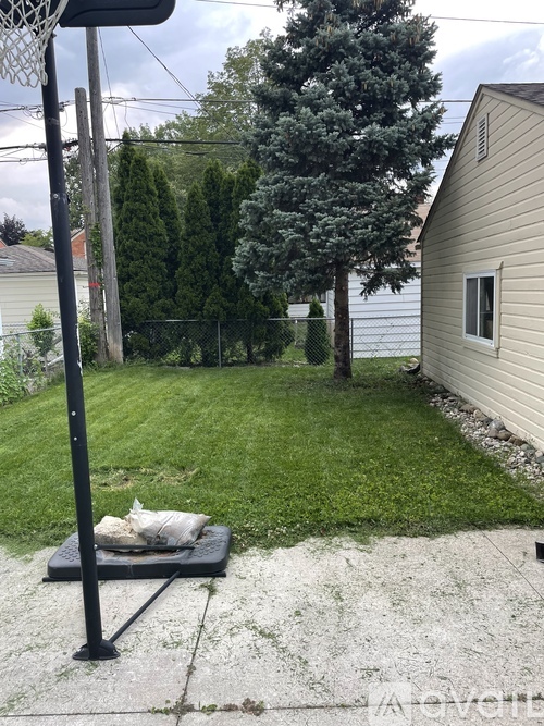A basketball hoop stands in a backyard with a bag of sand on the ground.