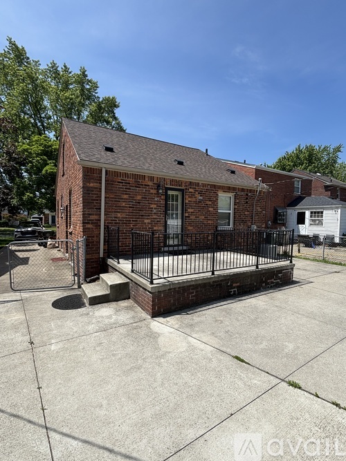 A small brick building with a black iron fence in front.