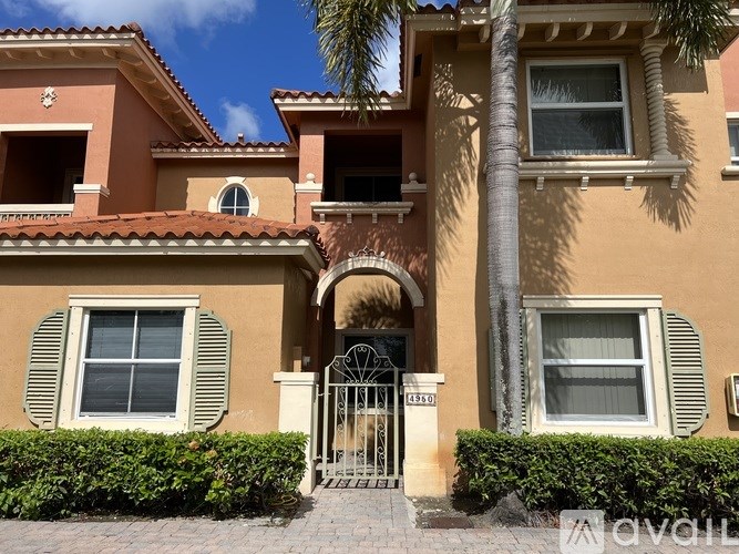 A house with a gate and a palm tree in front.