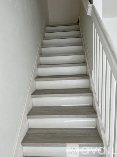 A set of stairs with white railings and grey steps.