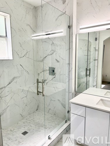 A bathroom with marble walls and a walk-in shower.