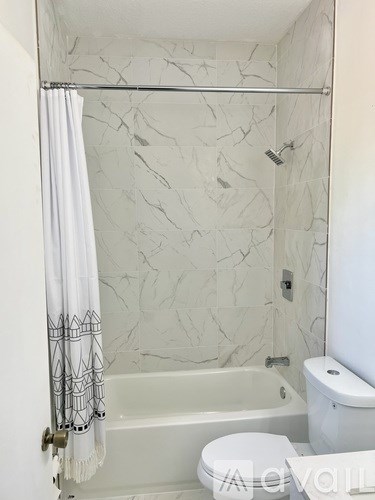 A white toilet sits next to a bathtub in a bathroom with marble walls.