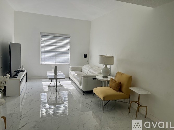 A living room with a white sofa, a yellow chair, and a television.