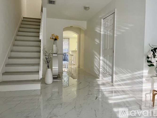 A hallway with marble flooring and a staircase.