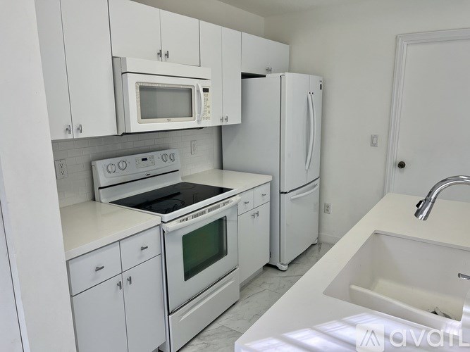 A white kitchen with a sink, stove, and refrigerator.