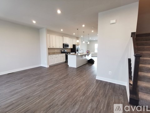 A spacious living room with a kitchen in the background.