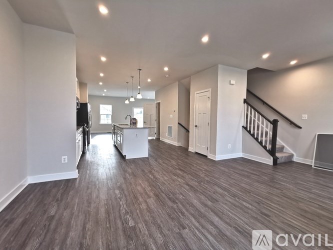 A spacious living room with wood flooring and a staircase.