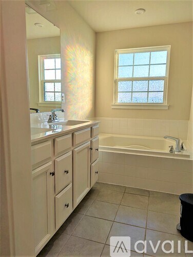 A bathroom with a tub, sink, and window.