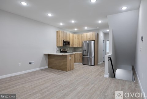 A kitchen with wooden cabinets and stainless steel appliances is available for rent.