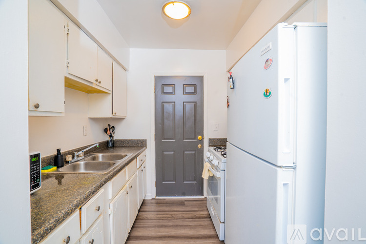 A kitchen with a white fridge and a grey door.