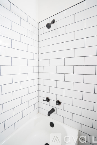 A white tiled bathroom with a white tub and faucet.