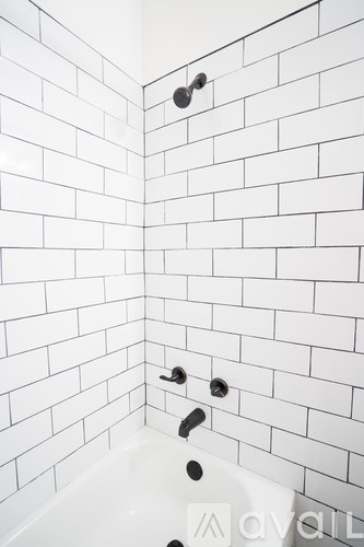 A white tiled bathroom with a white tub and faucet.