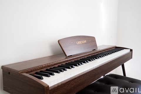 A wooden upright piano with a black leather stool in front of it.