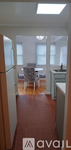 A kitchen with a refrigerator, sink, and a dining table with chairs.