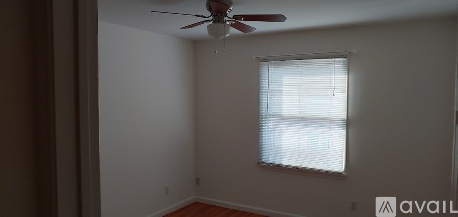 A room with a ceiling fan and a window with blinds.