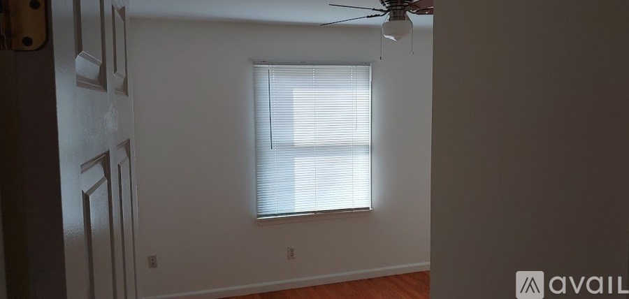 A room with a window covered by white blinds and a ceiling fan.
