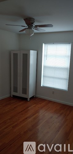 A room with a ceiling fan and a window with blinds.