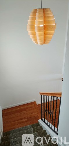 A hanging lamp with orange panels is suspended above a staircase.