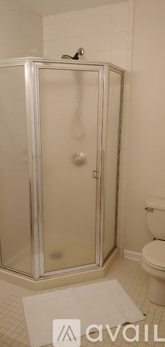 A white bathroom with a glass shower door and a white toilet.