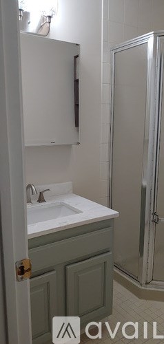 A bathroom with a white sink and a grey cabinet.