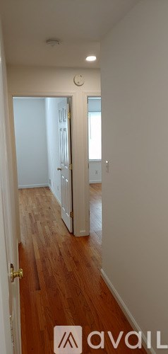 A hallway with wooden floors and white walls.