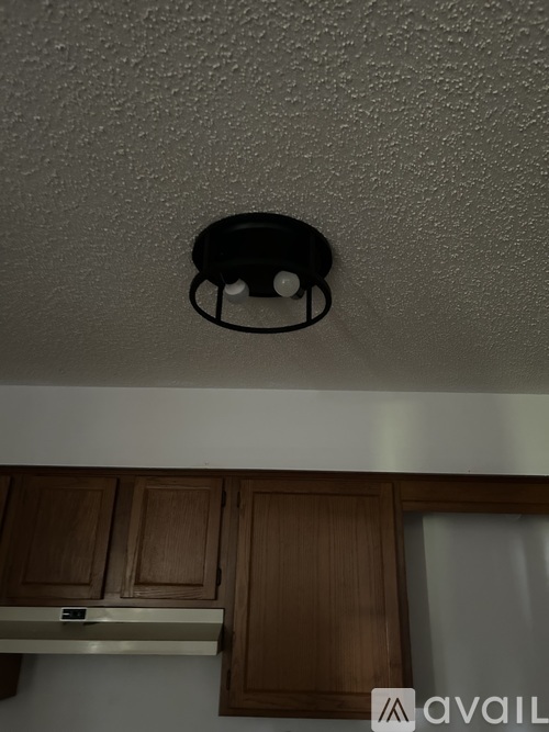 A black smoke detector is mounted on a white ceiling.