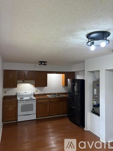 A kitchen with brown cabinets and a black refrigerator.