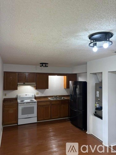 A kitchen with brown cabinets and a black refrigerator.
