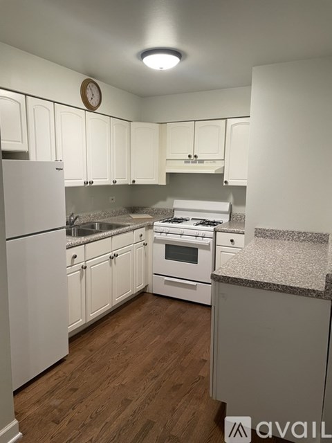 A kitchen with white cabinets and a wooden floor.