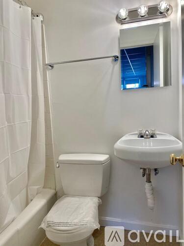 A white toilet with a white sink and a white shower curtain.
