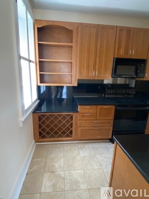 A kitchen with wooden cabinets and black countertops.