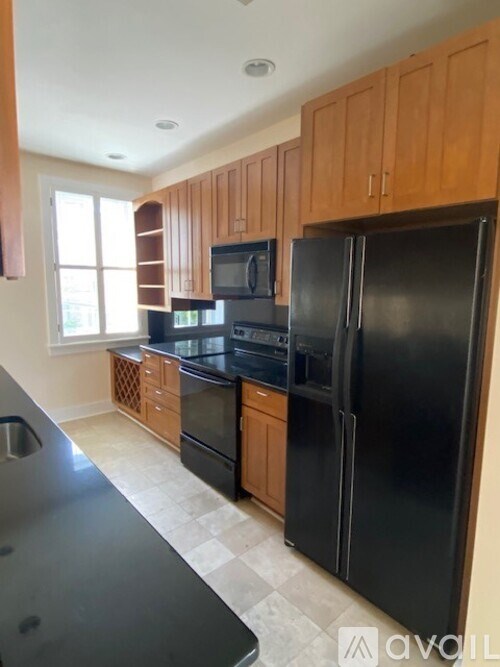 A kitchen with black appliances and wooden cabinets.