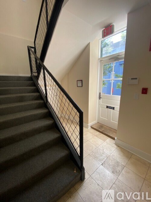 A staircase with a black railing and a white door at the top.