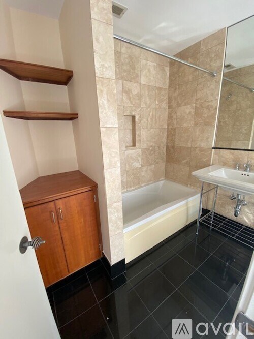 A bathroom with a tub, sink, and wooden cabinet.