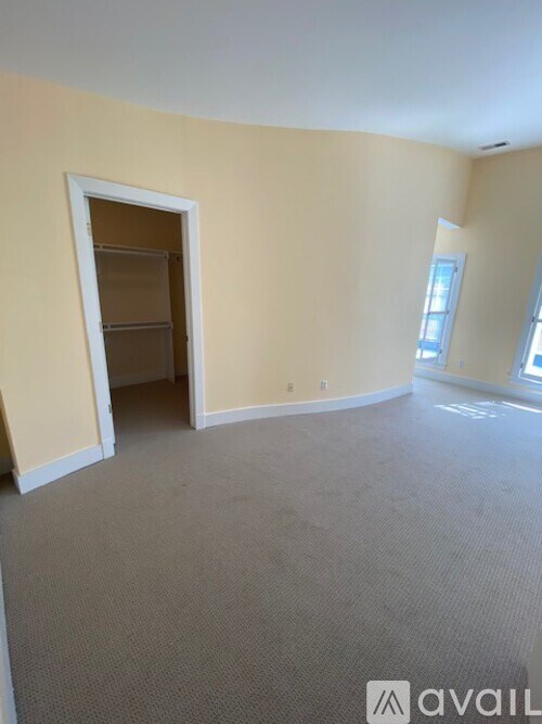 A room with a carpeted floor and a doorway leading to another room.