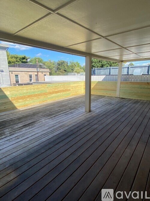 A wooden deck with a white roof and a fence in the background.
