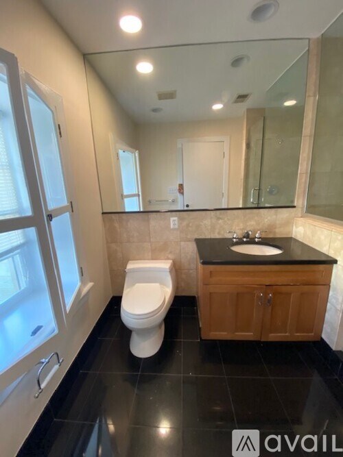 A bathroom with a toilet, sink, and mirror.