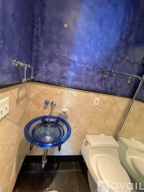 A bathroom with a blue glass shower seat and a white toilet.