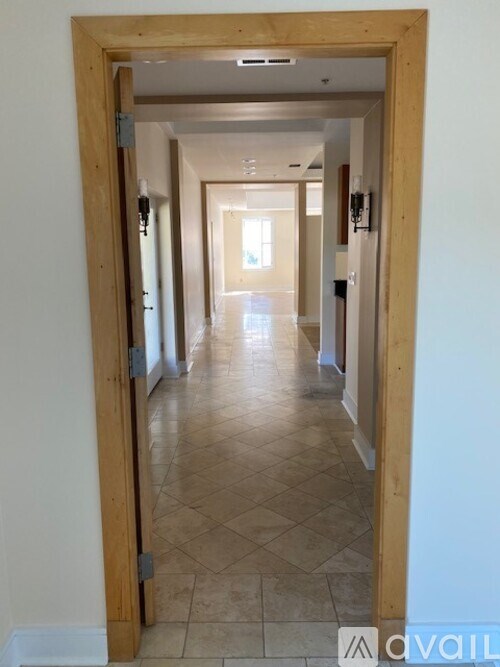 A hallway with tiled flooring and white walls.